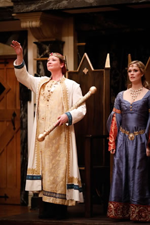 Photo of Richard in gold robe, holding sceptor, hand upraised, in front of throne, with Queen Isabel in blue dress beside him